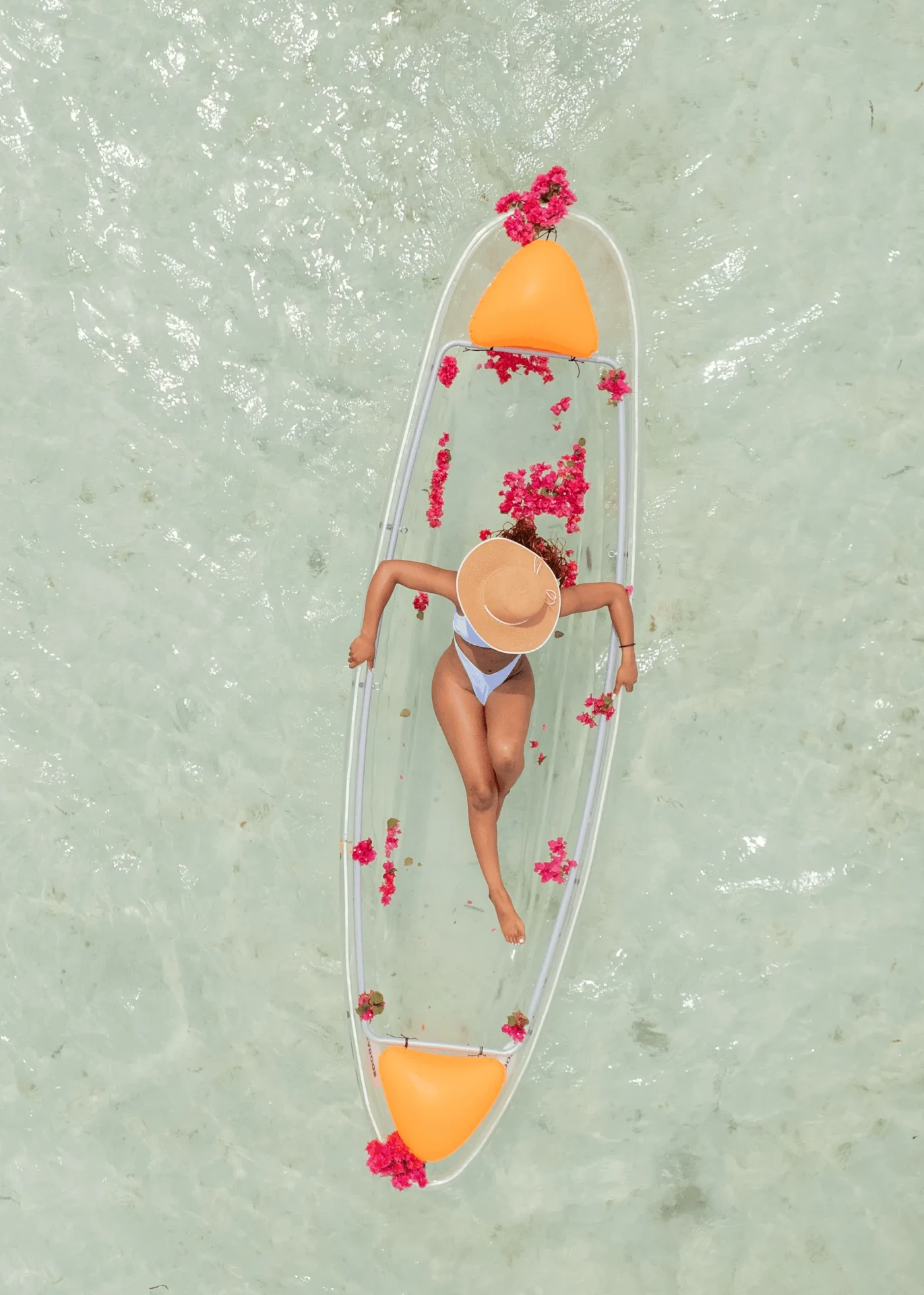 Aerial view with sun hat and pink flowers in a clear kayak, kayak photography in Zanzibar