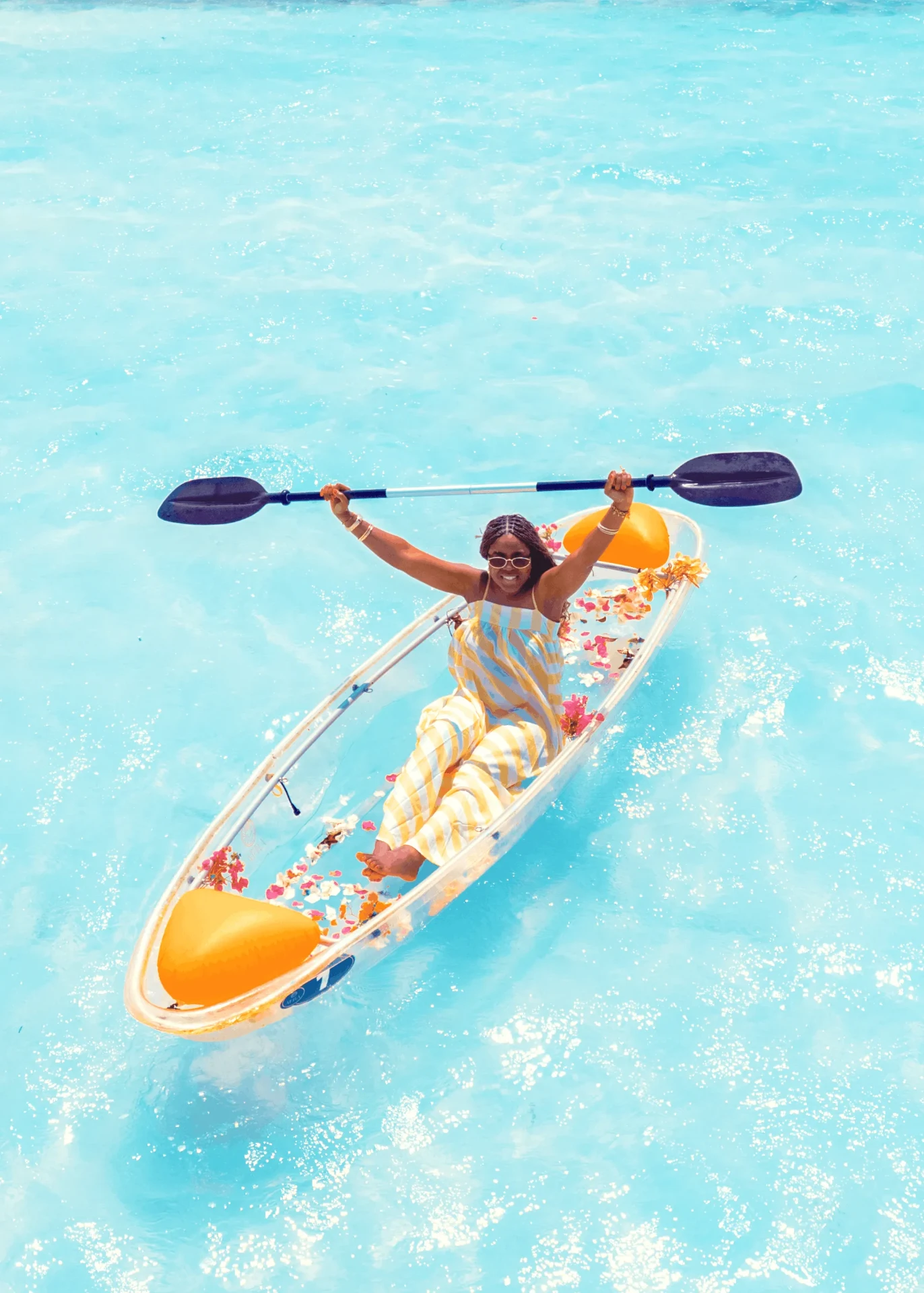 Paddle raised overhead in bright blue lagoon water, kayak photography in Zanzibar