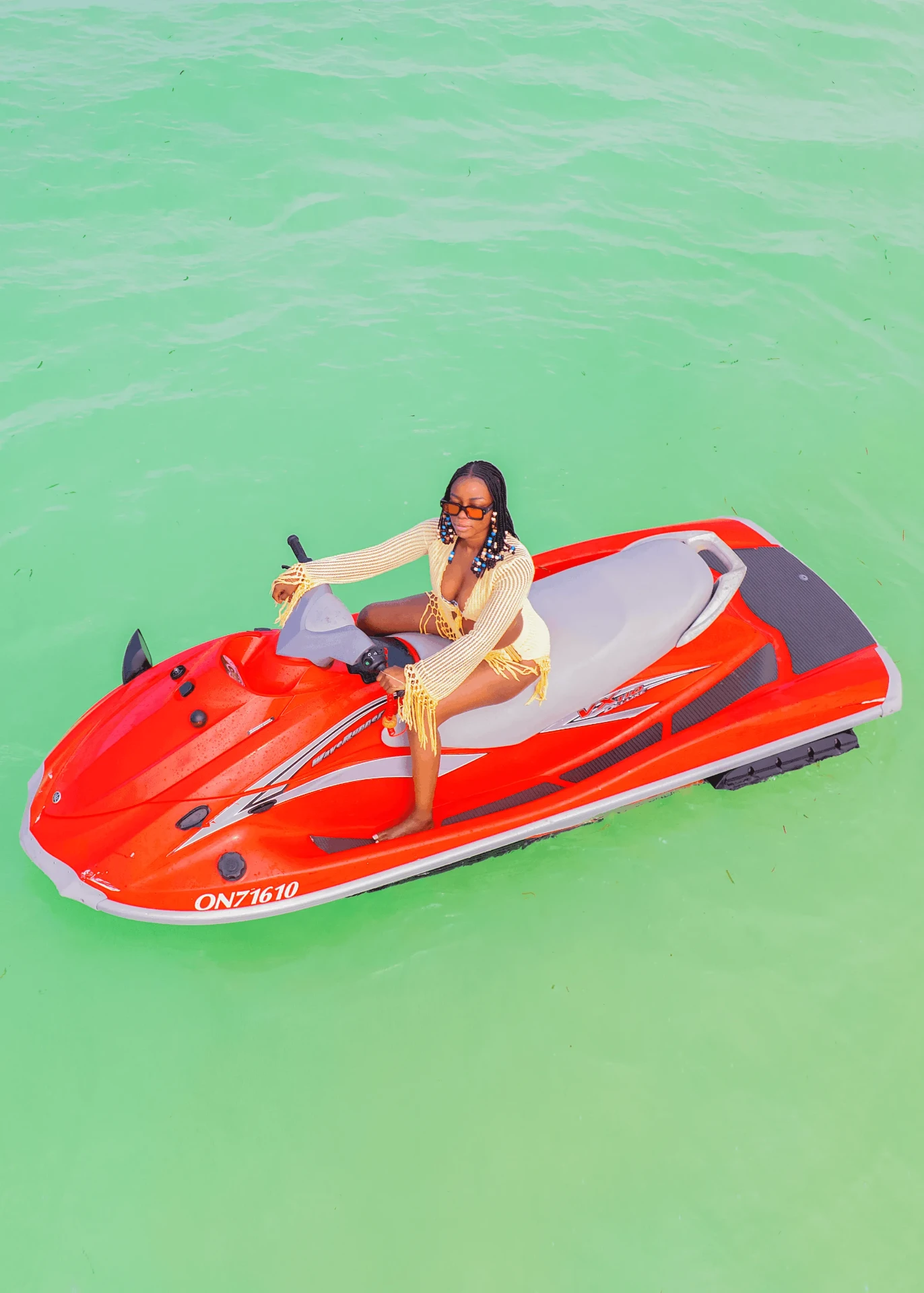 Rider posing on a red jet ski in green lagoon water, jet ski photography in Zanzibar
