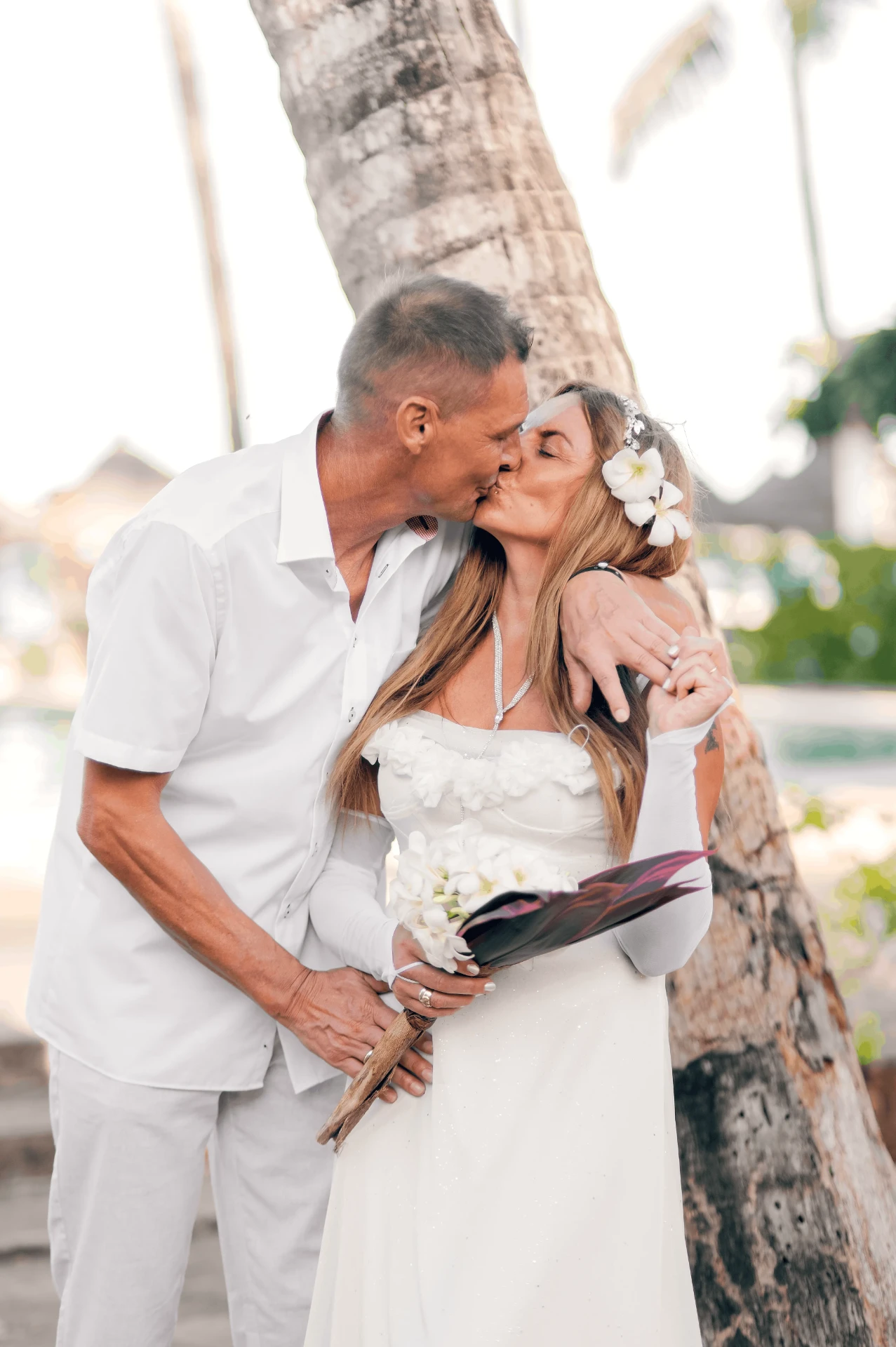 The couple kissing beneath a palm tree, wedding photography in Zanzibar