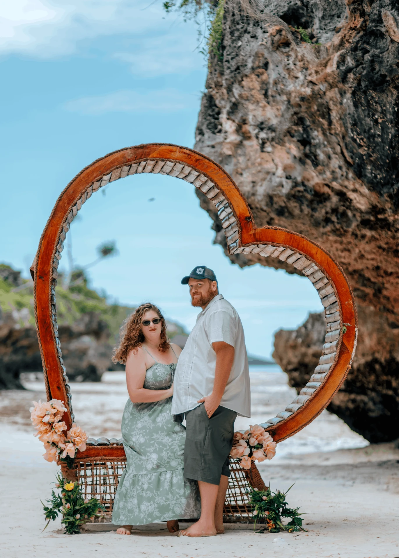 Posing inside a heart-shaped wooden beach frame, couple photoshoot in Zanzibar